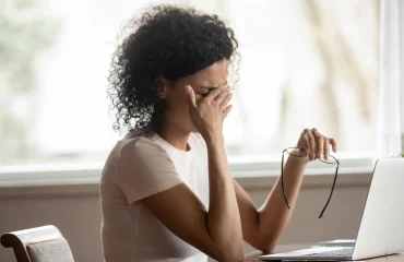 Photo exhausted african american young woman sit at table working take off glasses suffer from blurry vision or dizziness tired biracial female struggle with migraine or headache have sight problems