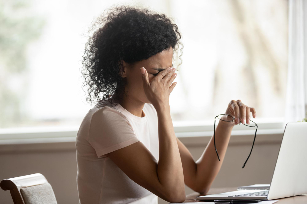 Photo exhausted african american young woman sit at table working take off glasses suffer from blurry vision or dizziness tired biracial female struggle with migraine or headache have sight problems