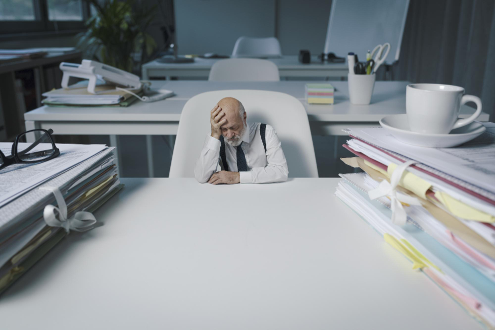 Photo tiny businessman sitting at office desk and thinking he is desperate and exhausted blank copy space