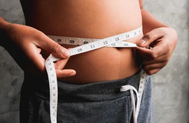Photo midsection of overweight person measuring waist with tape