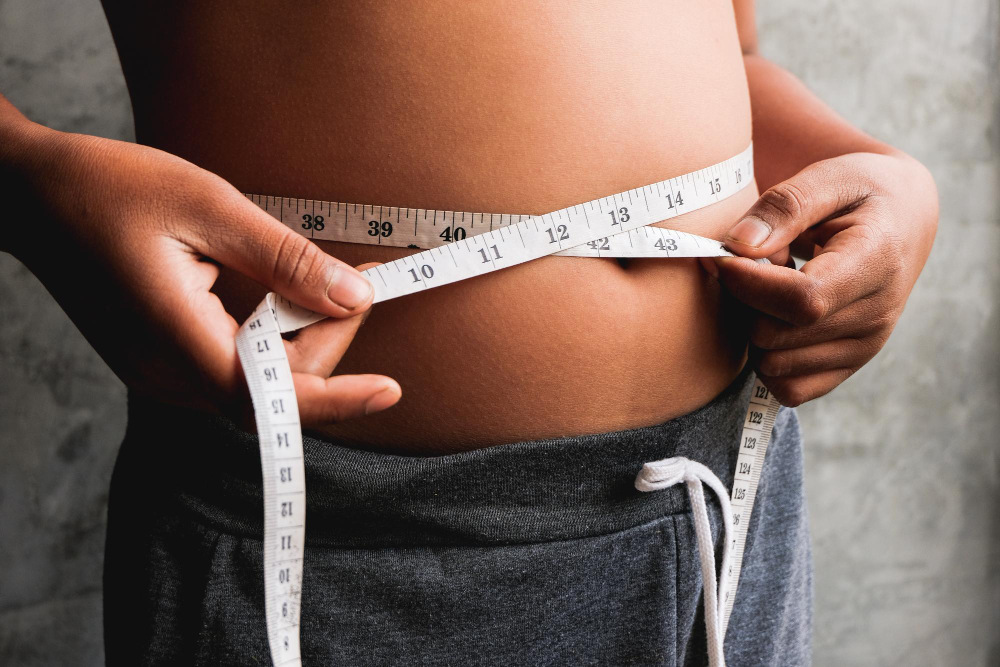 Photo midsection of overweight person measuring waist with tape