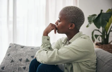 Woman thinking and depression on sofa for sad memory mental health risk and anxiety of debt stress worry and lonely african person remember trauma of abuse broken heart or doubt decision at home