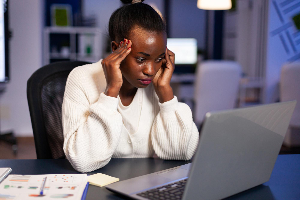 Young depressed or anxious african american Woman using LAPTOP while sitting on table