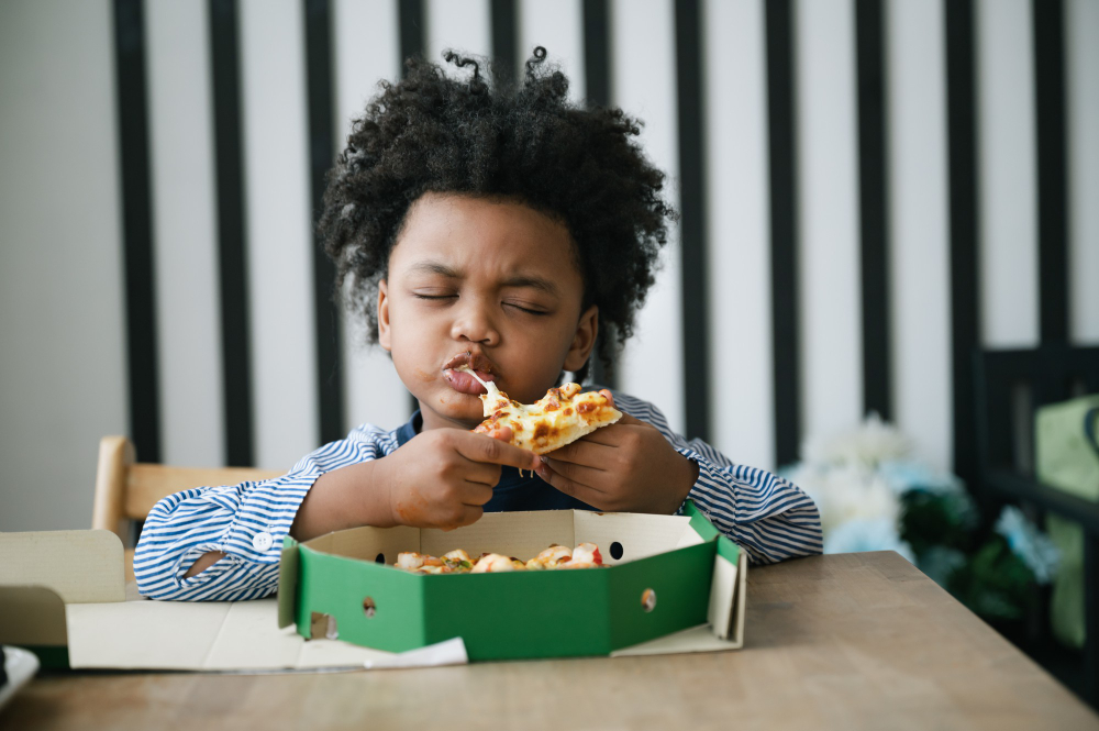 Happy African American child eating pizza on table