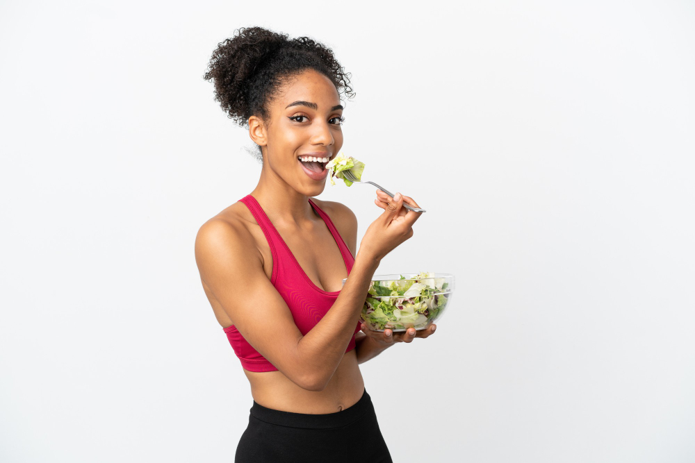 Young african american woman with salad isolated on white background holding a bowl of salad with happy expression