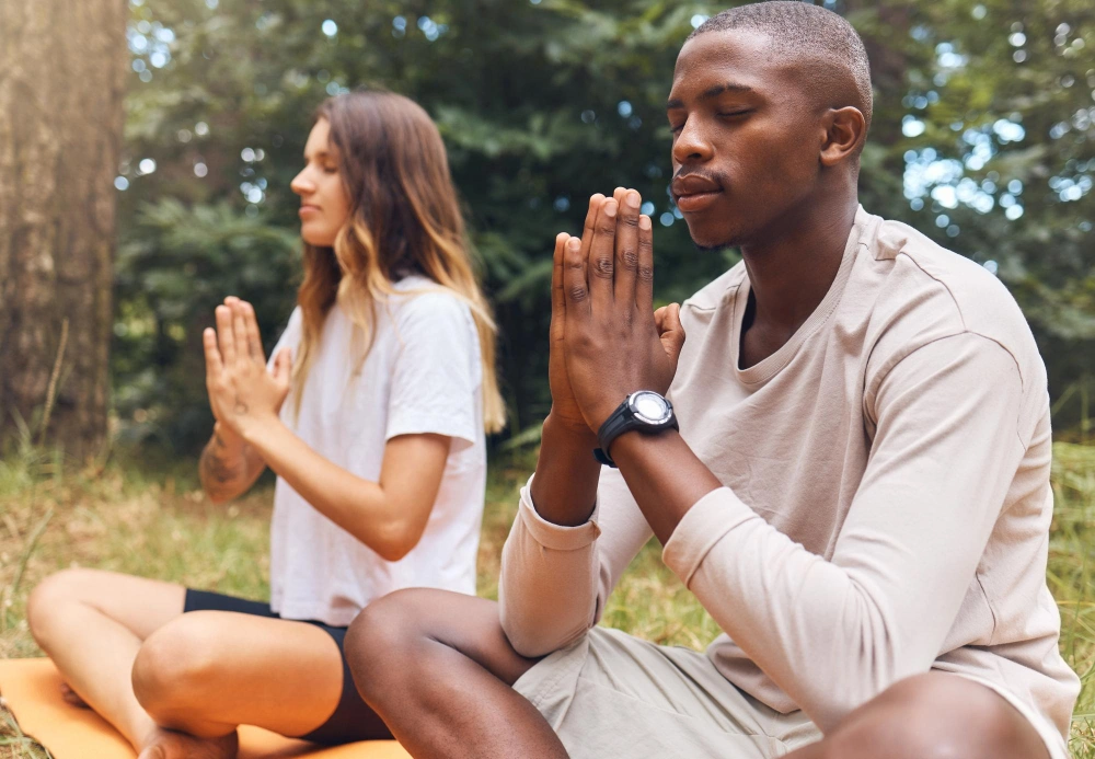 Yoga man and woman in prayer hand pose together in nature grass and outdoors Zen meditation and athletic friends doing pilates outside on the ground or field for health fitness and wellness