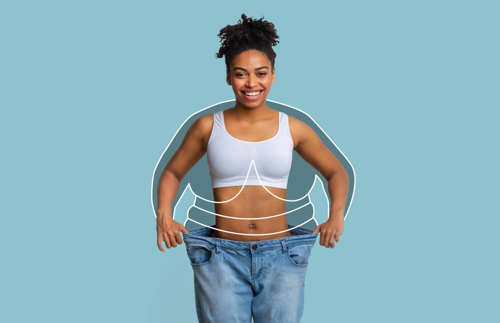 Smiling millennial slim african american female in big jeans enjoying weight loss result with fat abstract body around