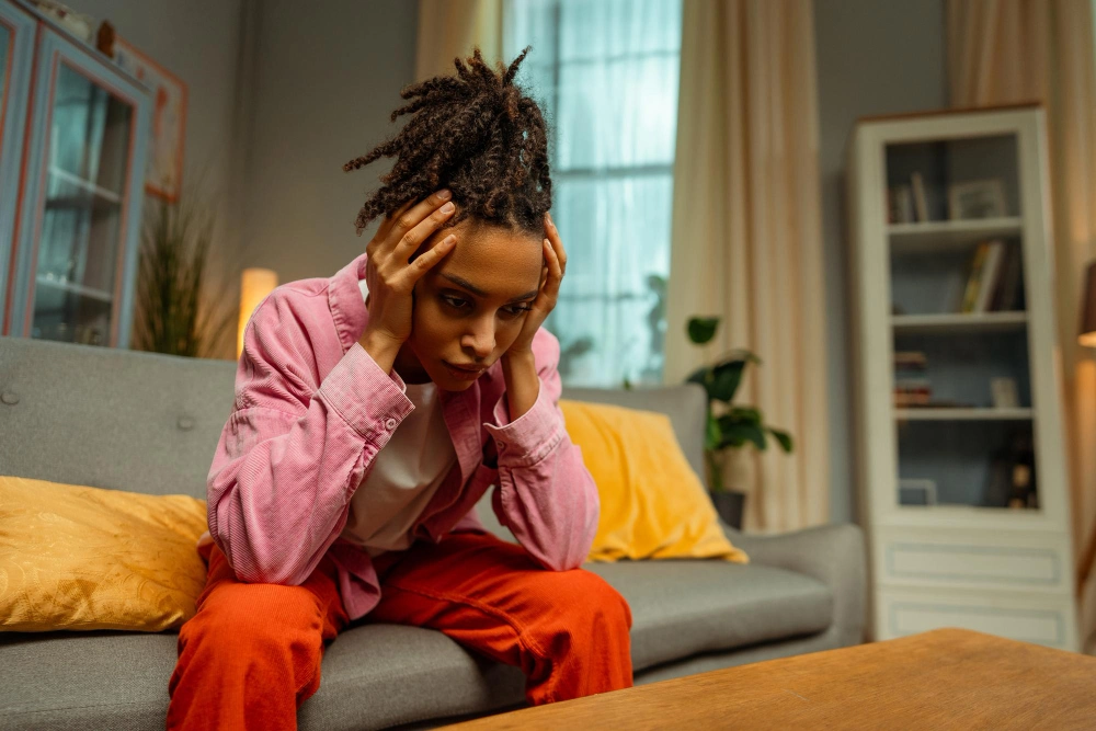 Portrait of tired lonely African American woman having Panic Attacks and Panic Disorder sitting on sofa at home