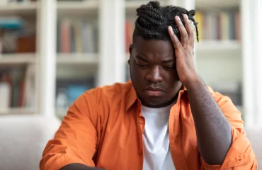 OCD black guy sitting alone on couch at home