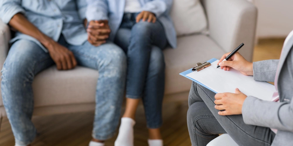 Afro couple holding hands on couch during marriage counseling session