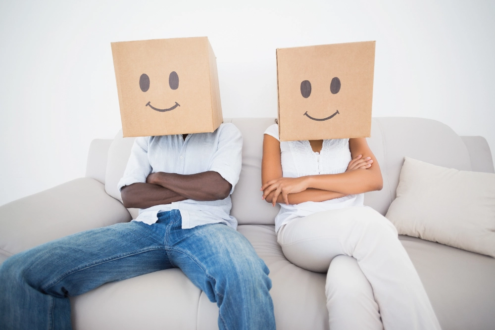 Couple sitting on couch together with boxes over head