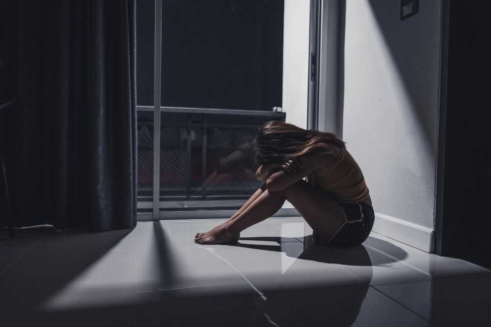 PTSD young woman sitting alone on the floor in the living room