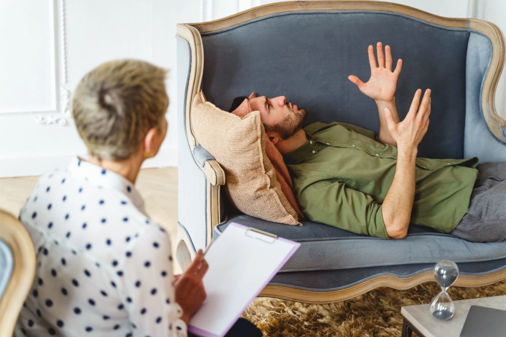 Side view of a young Caucasian man on the couch gesticulating during the therapy session