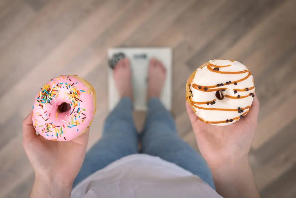 woman-stands-scales-holds-donuts-her-hands-top-view-copy-space