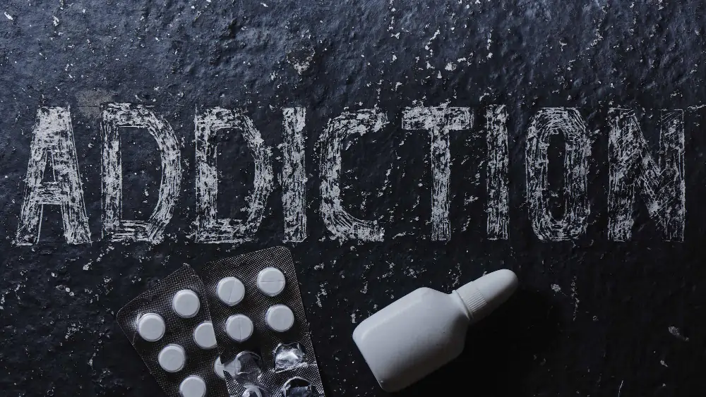 The concept of drug dependence, pills, nasal spray. Black background with white inscription addiction and medicines